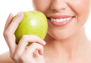 Kobieta trzyma jabłko i się uśmiecha